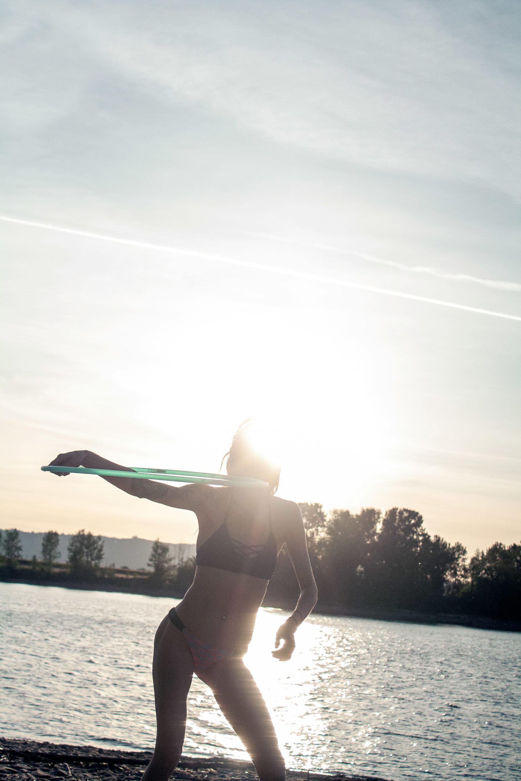 Woman stretching outdoors with a lake view, representing recovery and mobility