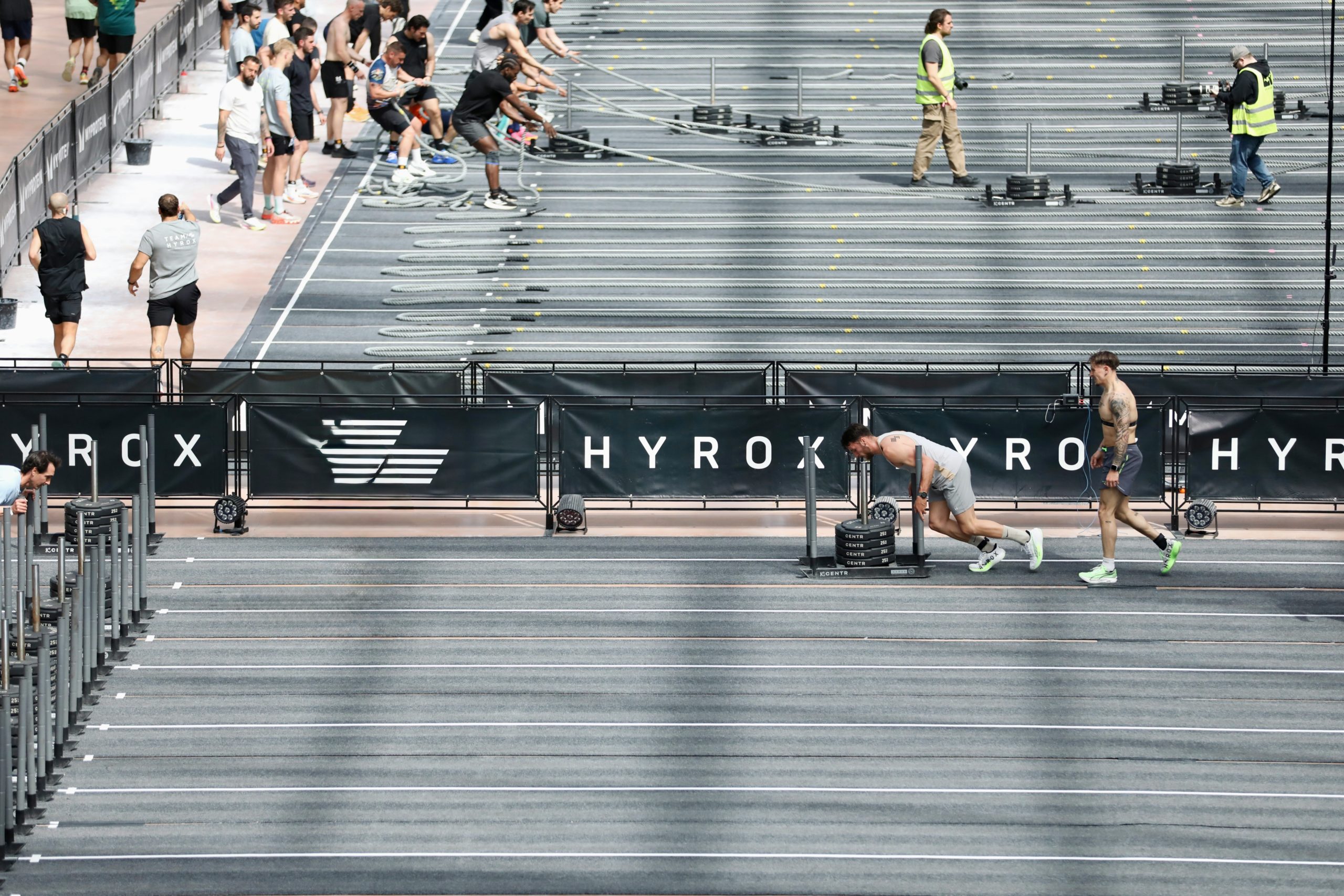 Athletes pushing sleds and running indoors, representing typical Hyrox training preparation