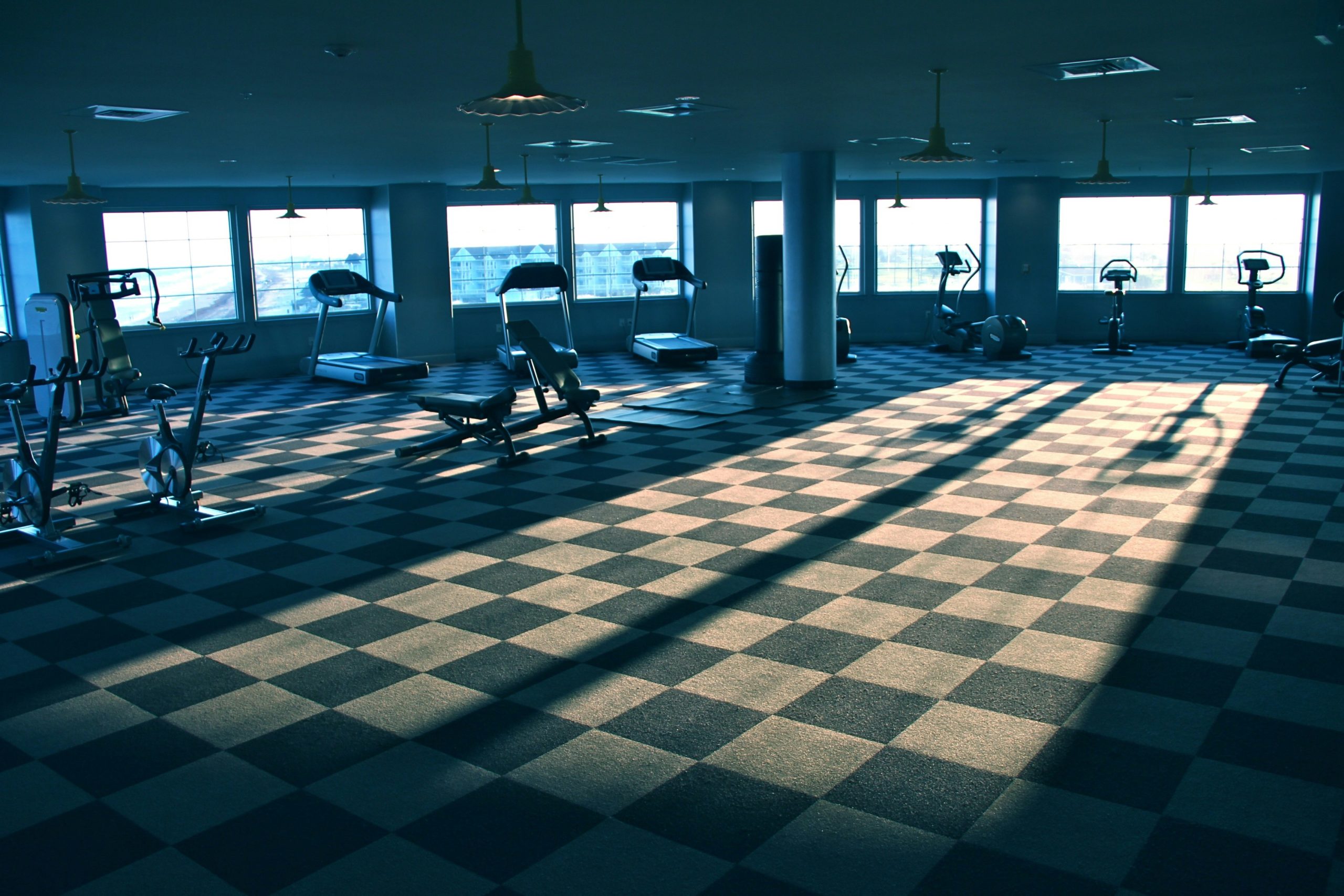 A wide angle shot of a clean modern gym interior with functional fitness equipment like sleds and rowers