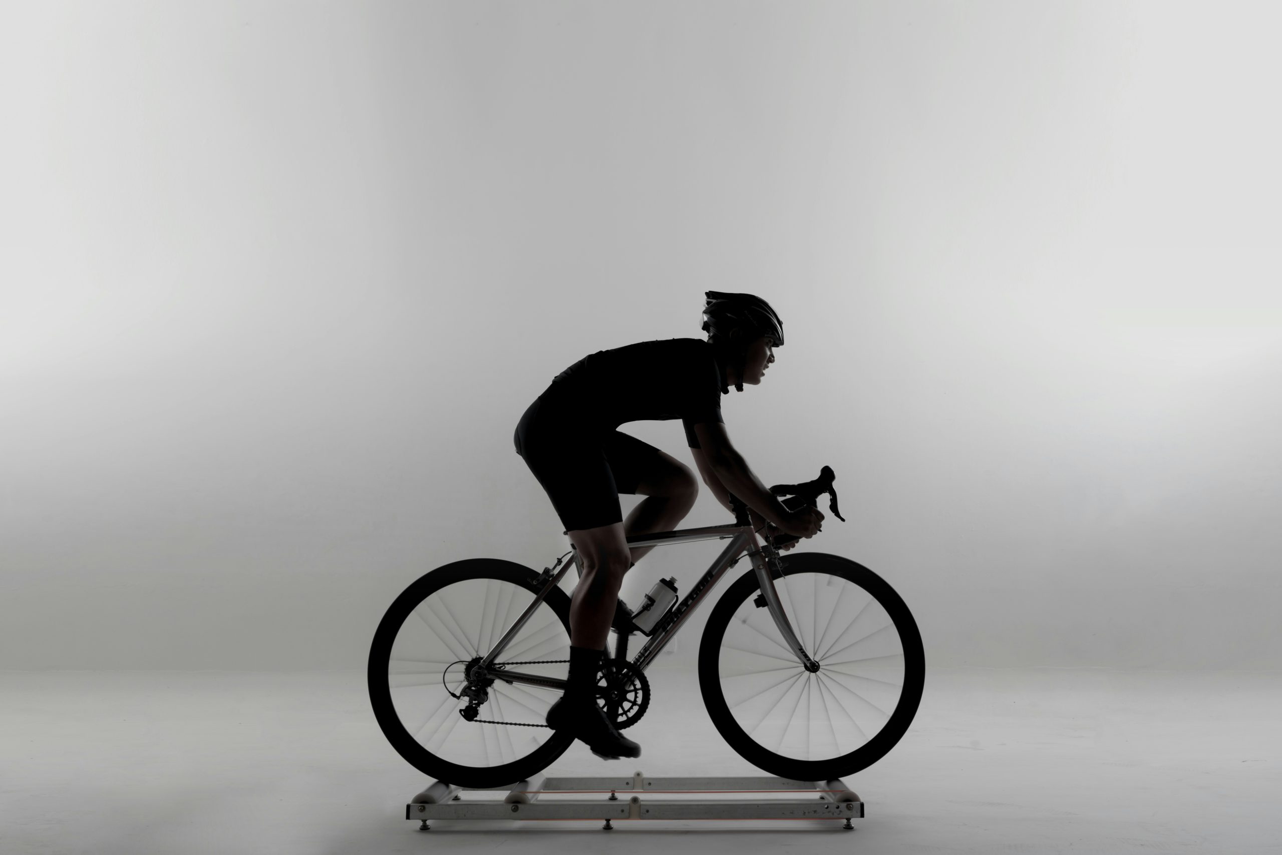 Indoor cycling class details, focusing on the spinning bike flywheel and legs in motion