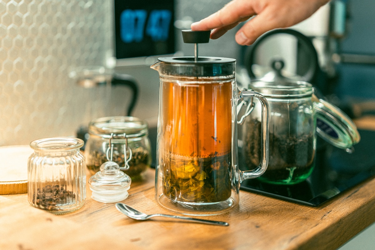 A person pours tea into a glass teapot