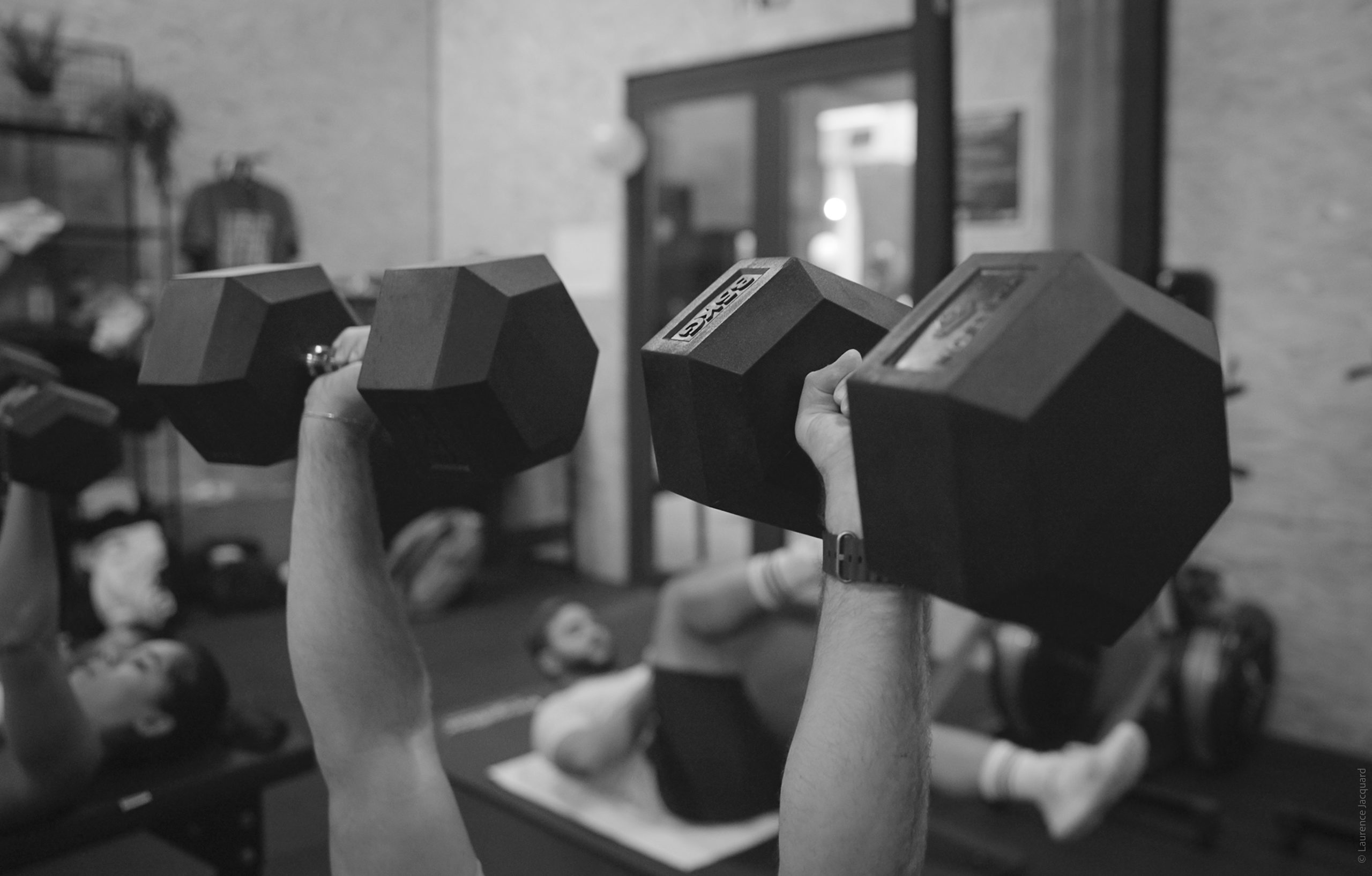 Un entraîneur observe une classe de groupe dans un centre de fitness fonctionnel avec des kettlebells et des racks, des ...