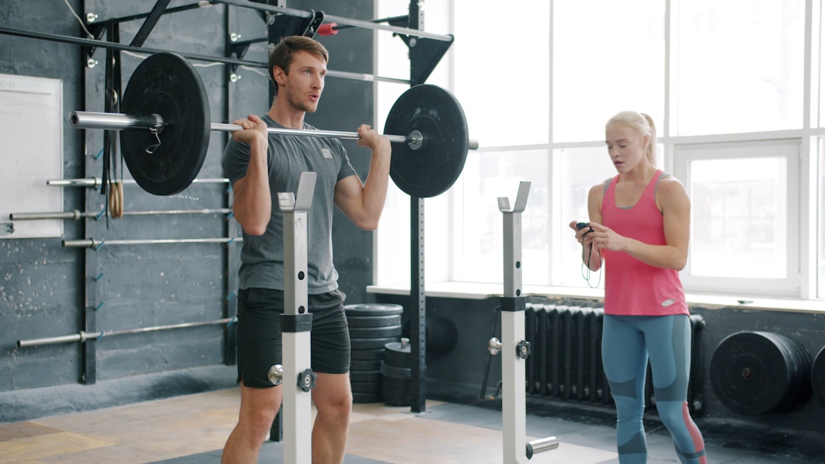 Deux personnes s'entraînant dans une salle de gym avec des équipements de musculation.