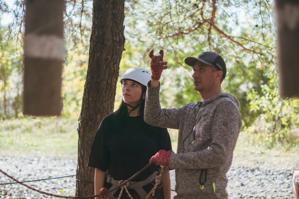 Instructor guiding a young woman in outdoor adventure activity.
