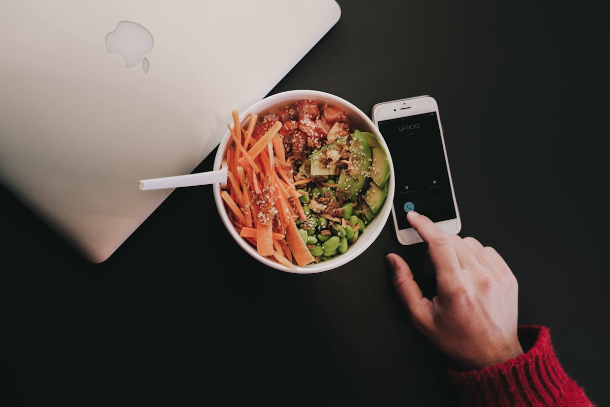 Bol de salade colorée avec légumes et smartphone.