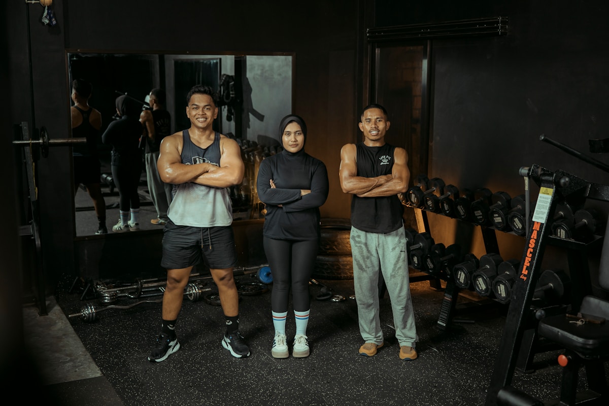 Trois personnes musclées posant dans une salle de gym.