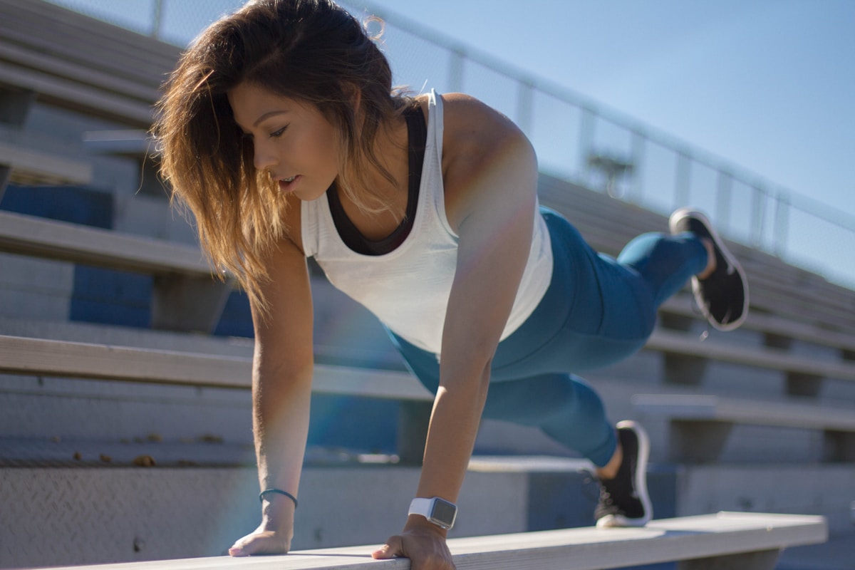Femme athlétique s'entraînant sur un banc de fitness extérieur.