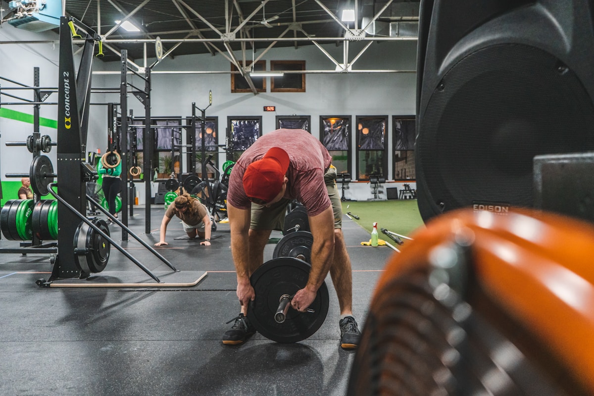 Salle de gym avec équipements d'entraînement et personnes s'entraînant.