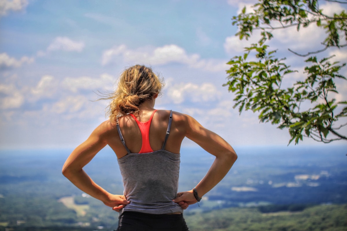 Femme athlétique contemplant le paysage depuis une montagne.
