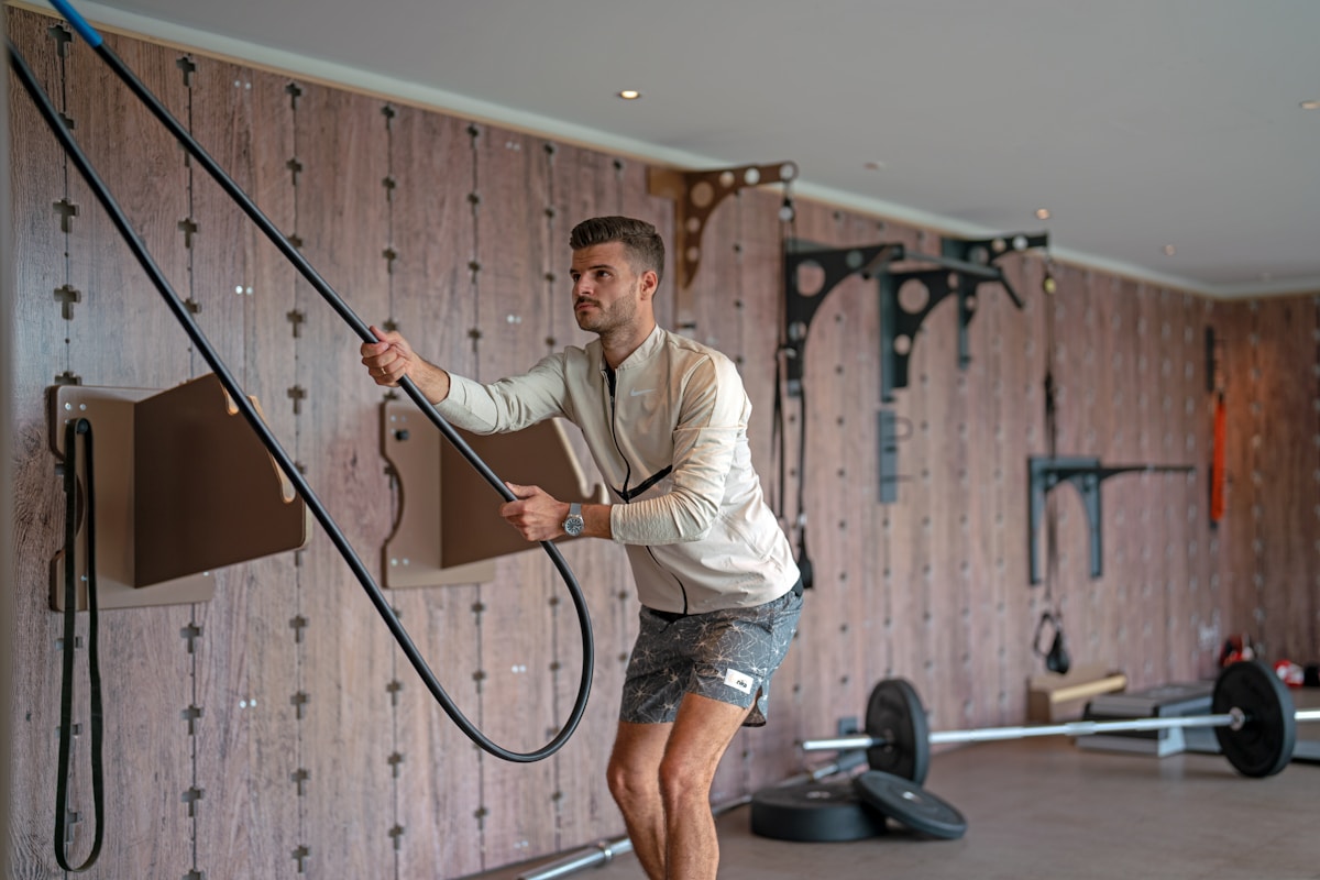 Homme musclé s'entraînant avec des cordes dans une salle de gym.