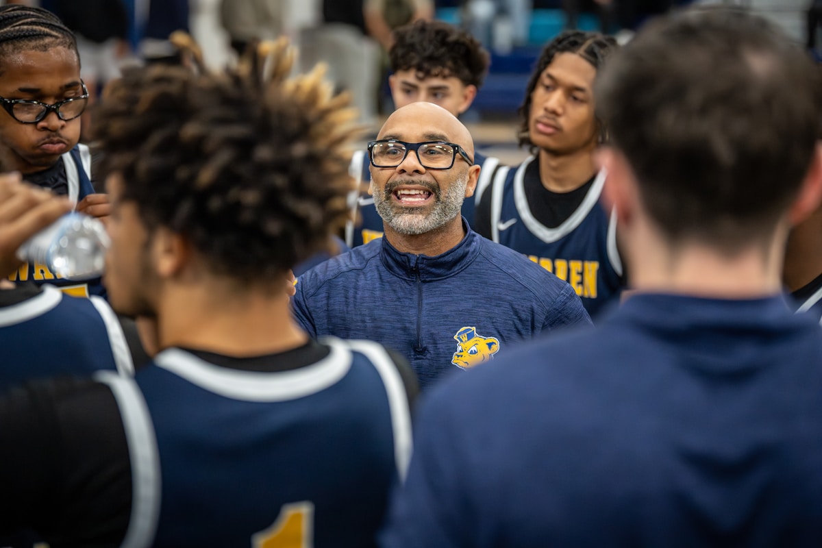 Équipe de basket-ball masculine diverse et engagée avec un entraîneur souriant.