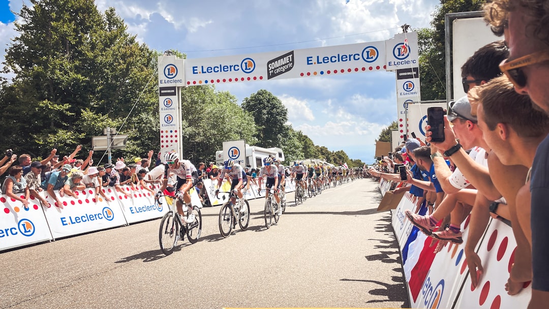 comment débuter la course à pied sans se blesser - Cyclists race past spectators under an e. leclerc archway