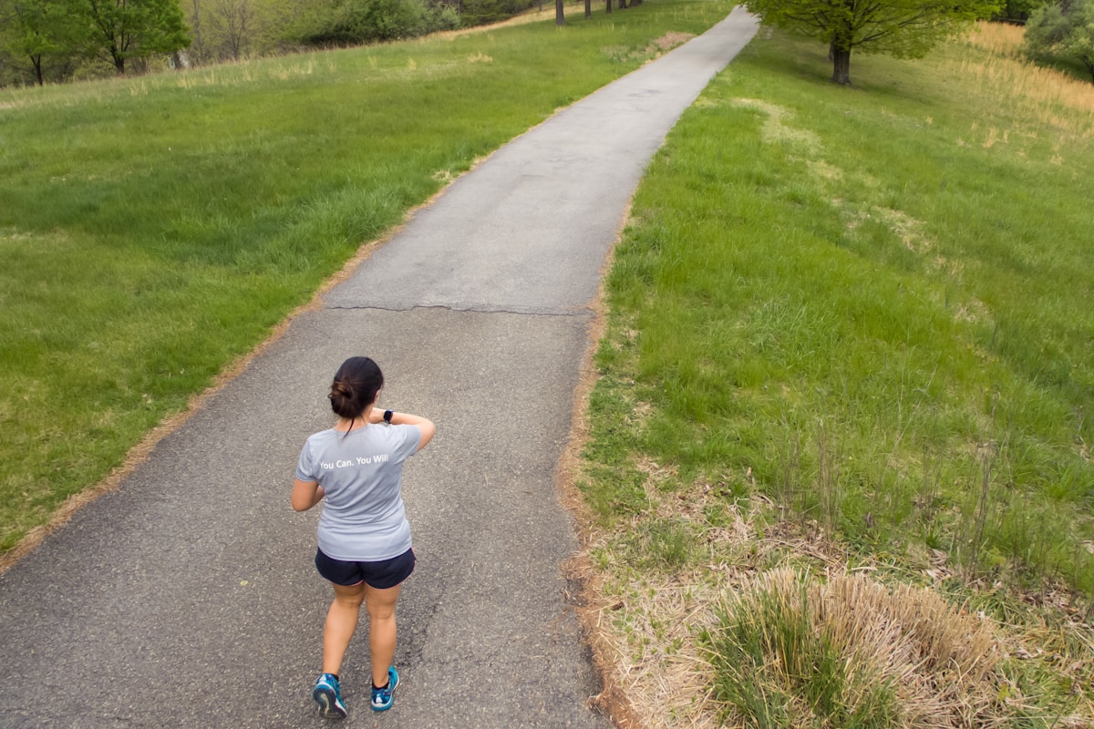 Femme marchant sur un chemin de campagne entouré de verdure.