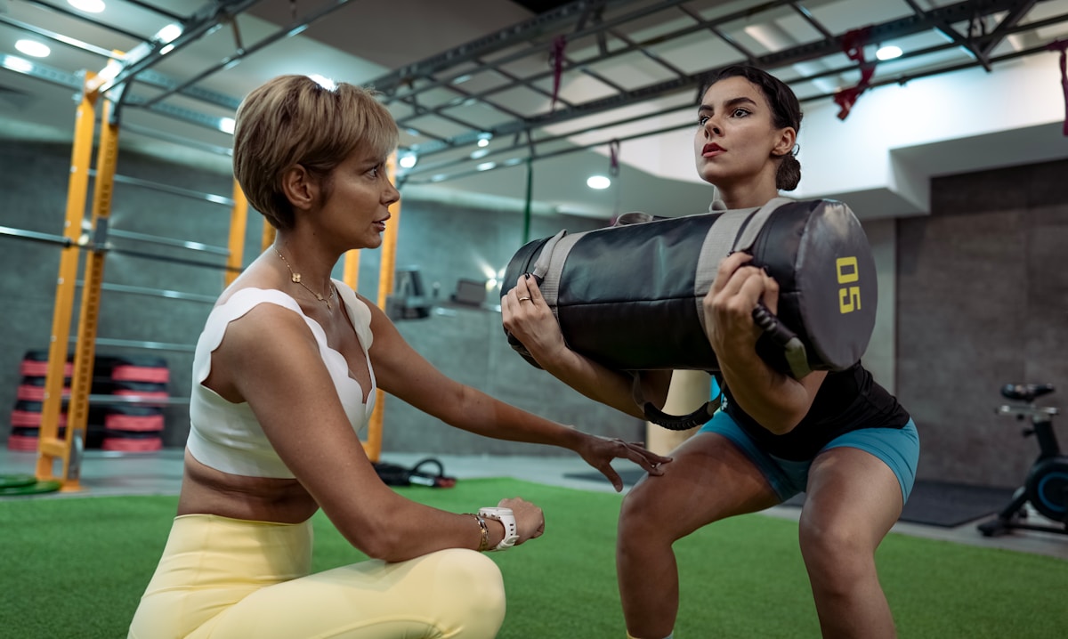 Deux femmes s'entraînant avec un sac de frappe dans une salle de sport.
