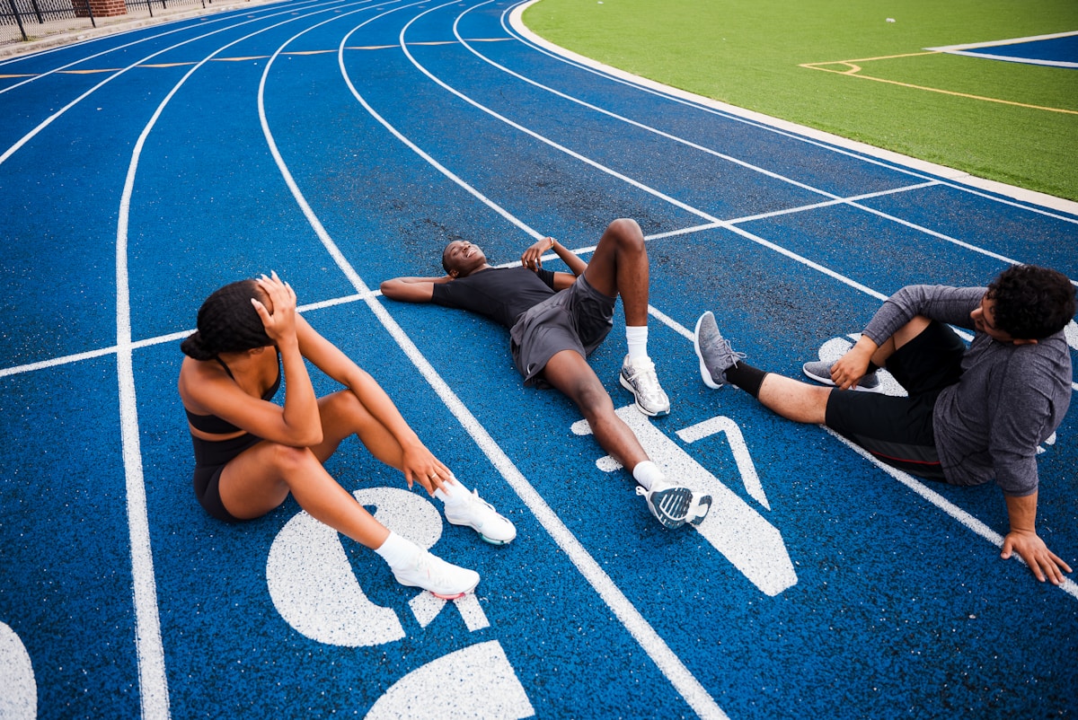 Athlètes se reposant sur une piste d'athlétisme bleue.