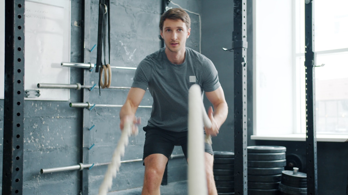 Homme musclé s'entraînant avec haltères dans une salle de gym.