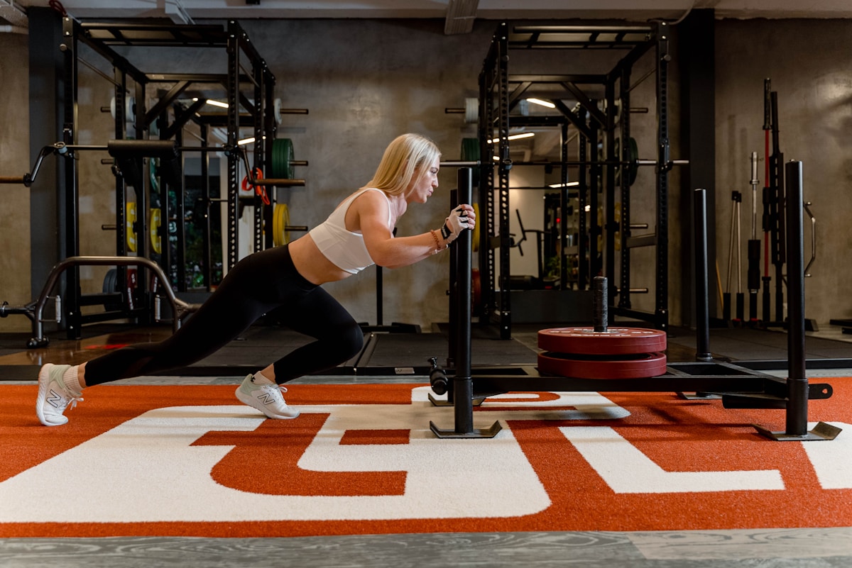 Femme athlétique s'entraînant dans une salle de gym avec équipements.