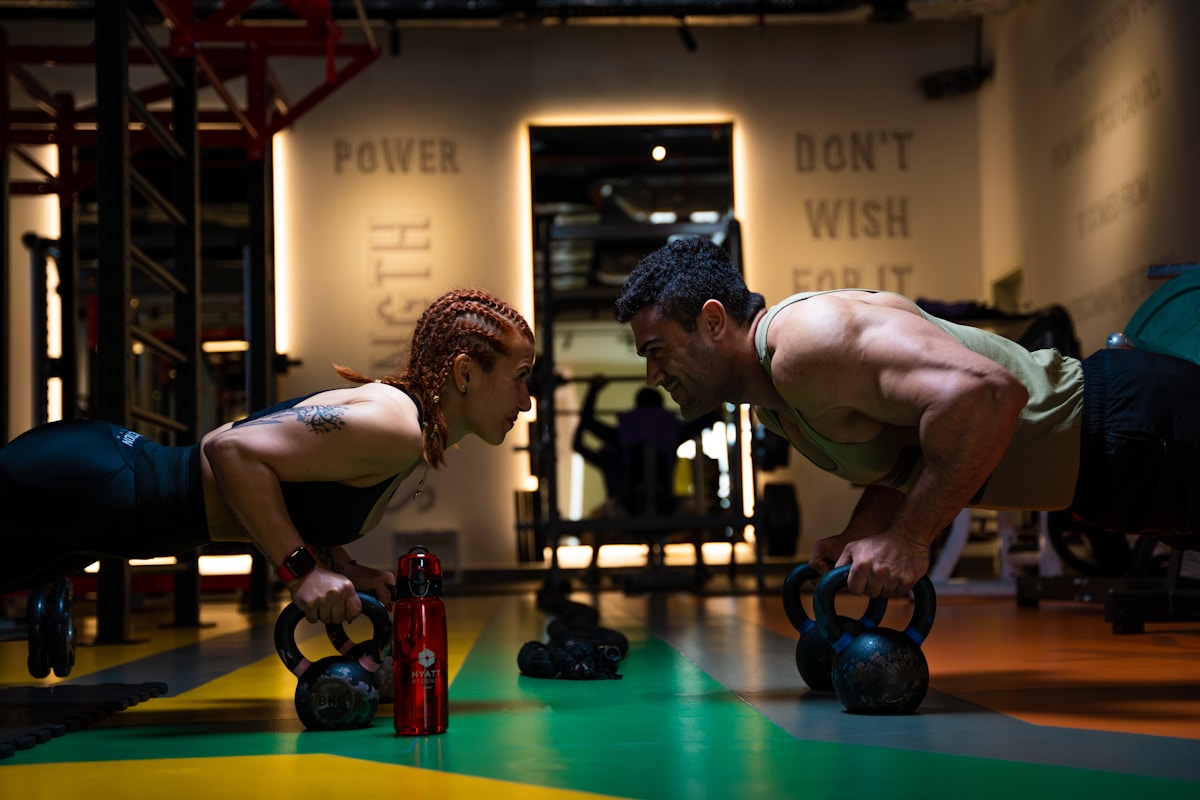Deux athlètes s'entraînent intensément dans une salle de gym.