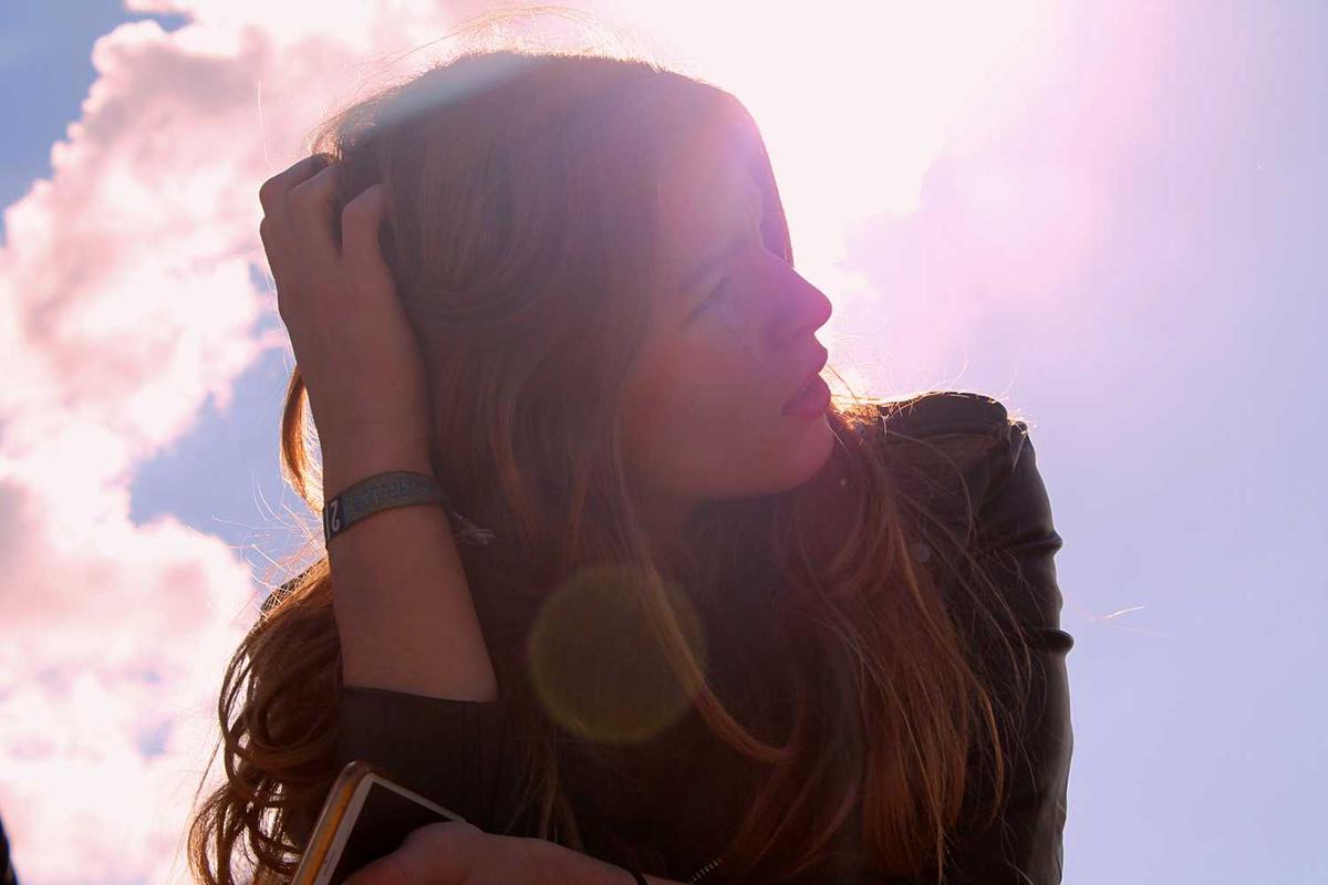 Femme regardant le ciel, main dans les cheveux.