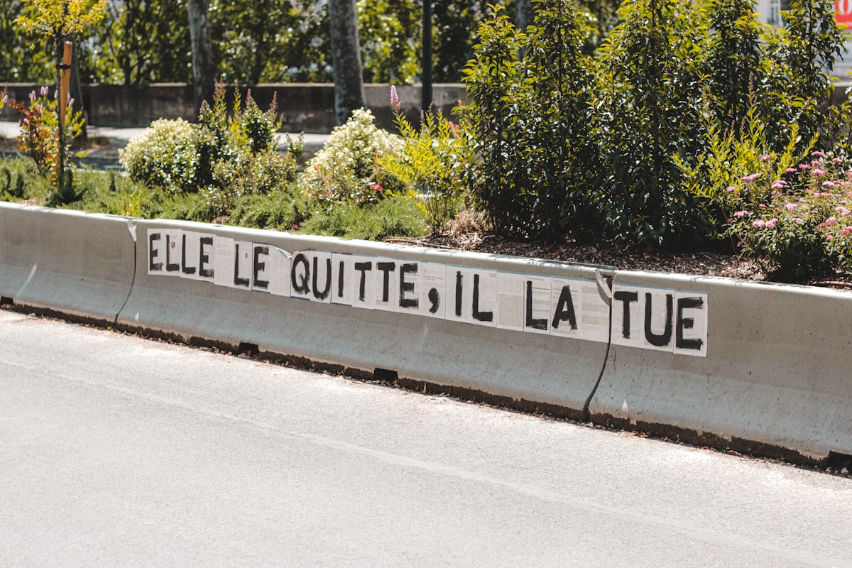 Graffiti sur un mur, message en français "Elle le quitte, il la tue".