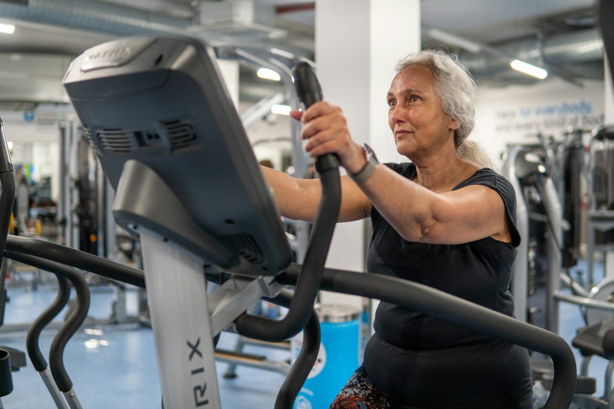 Femme âgée utilisant un vélo elliptique dans une salle de sport