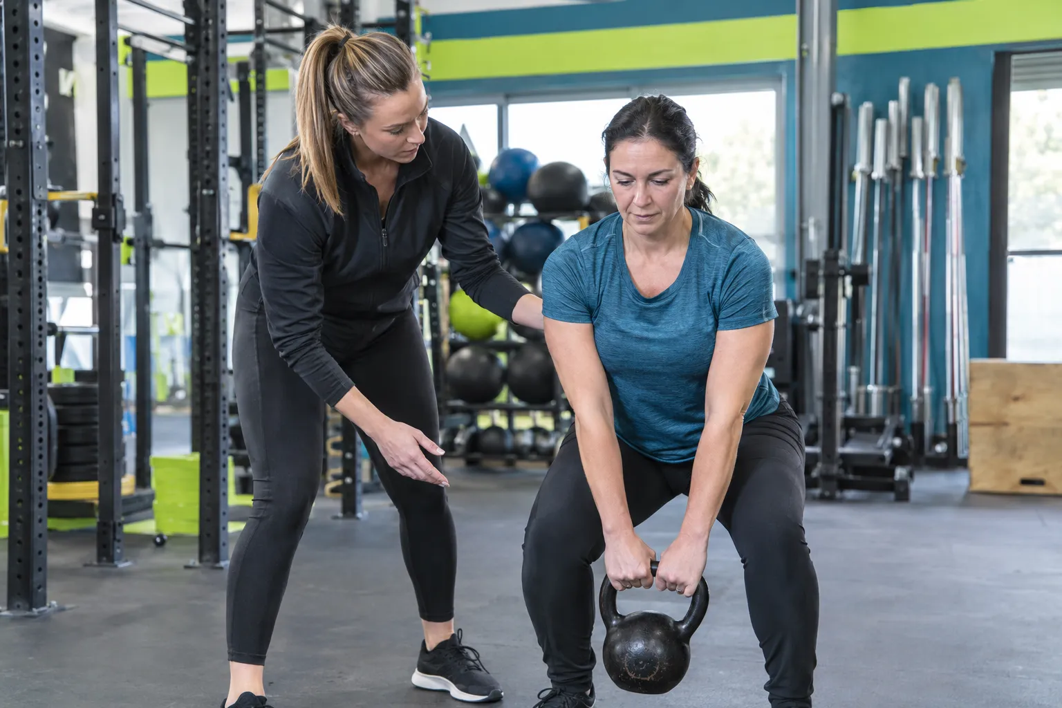 Coach guidant une femme pendant un soulevé de terre kettlebell en salle de sport