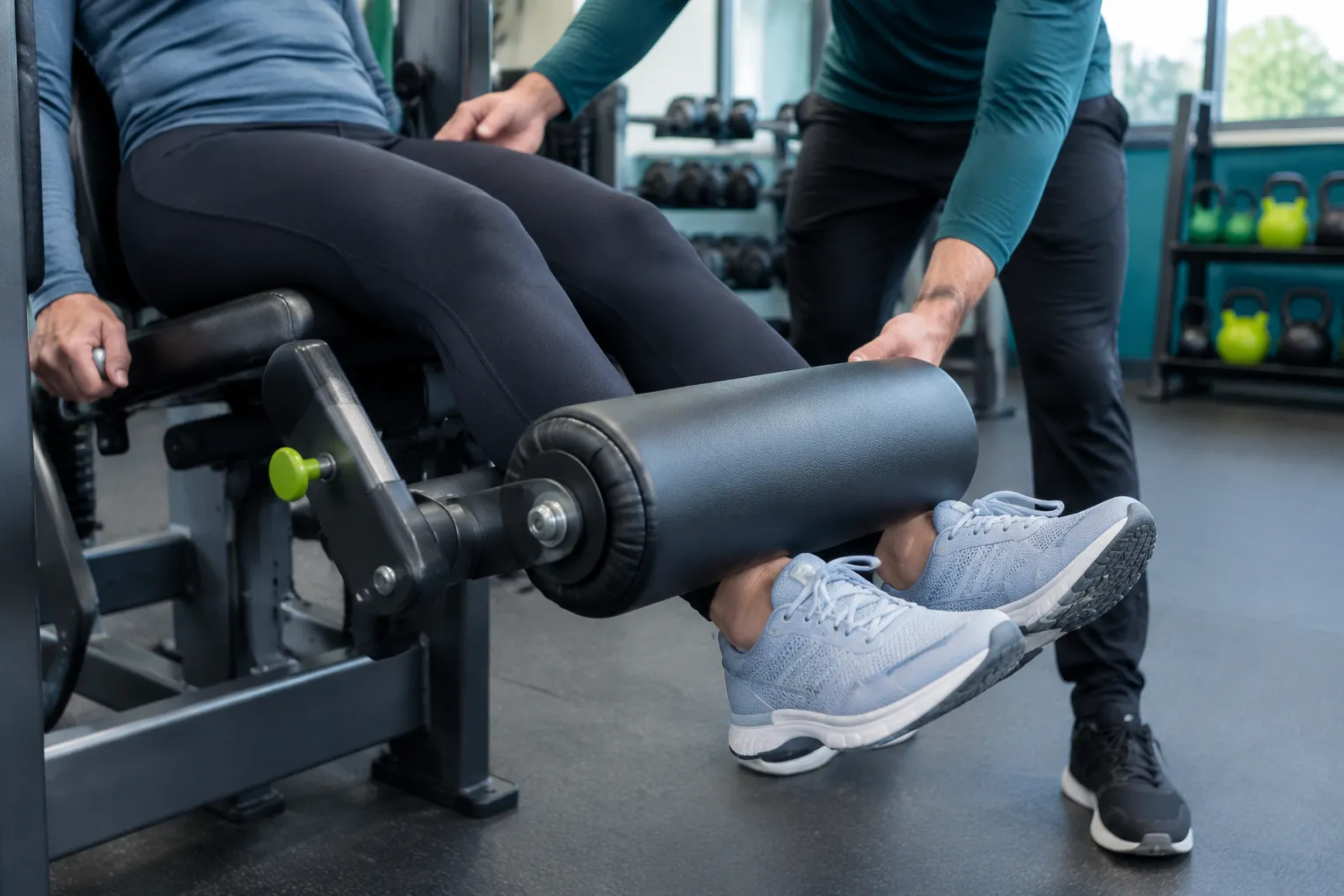 Femme réalisant une extension des jambes guidée par un entraîneur