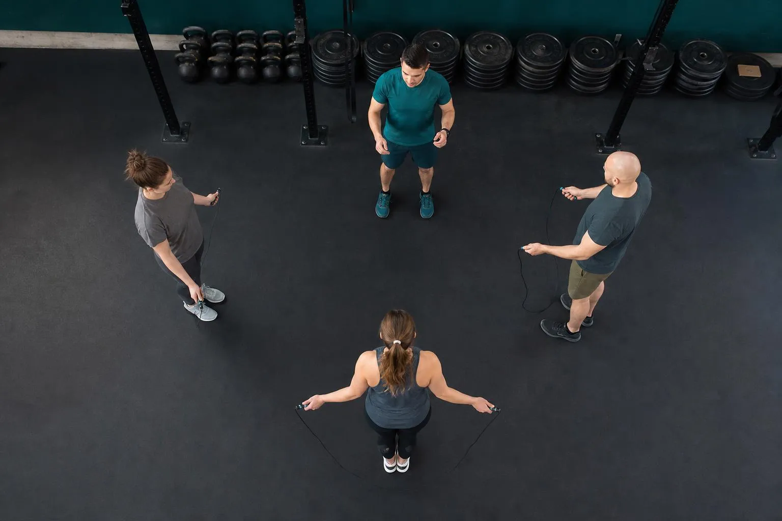 Quatre personnes s’entraînent à la corde à sauter en salle.
