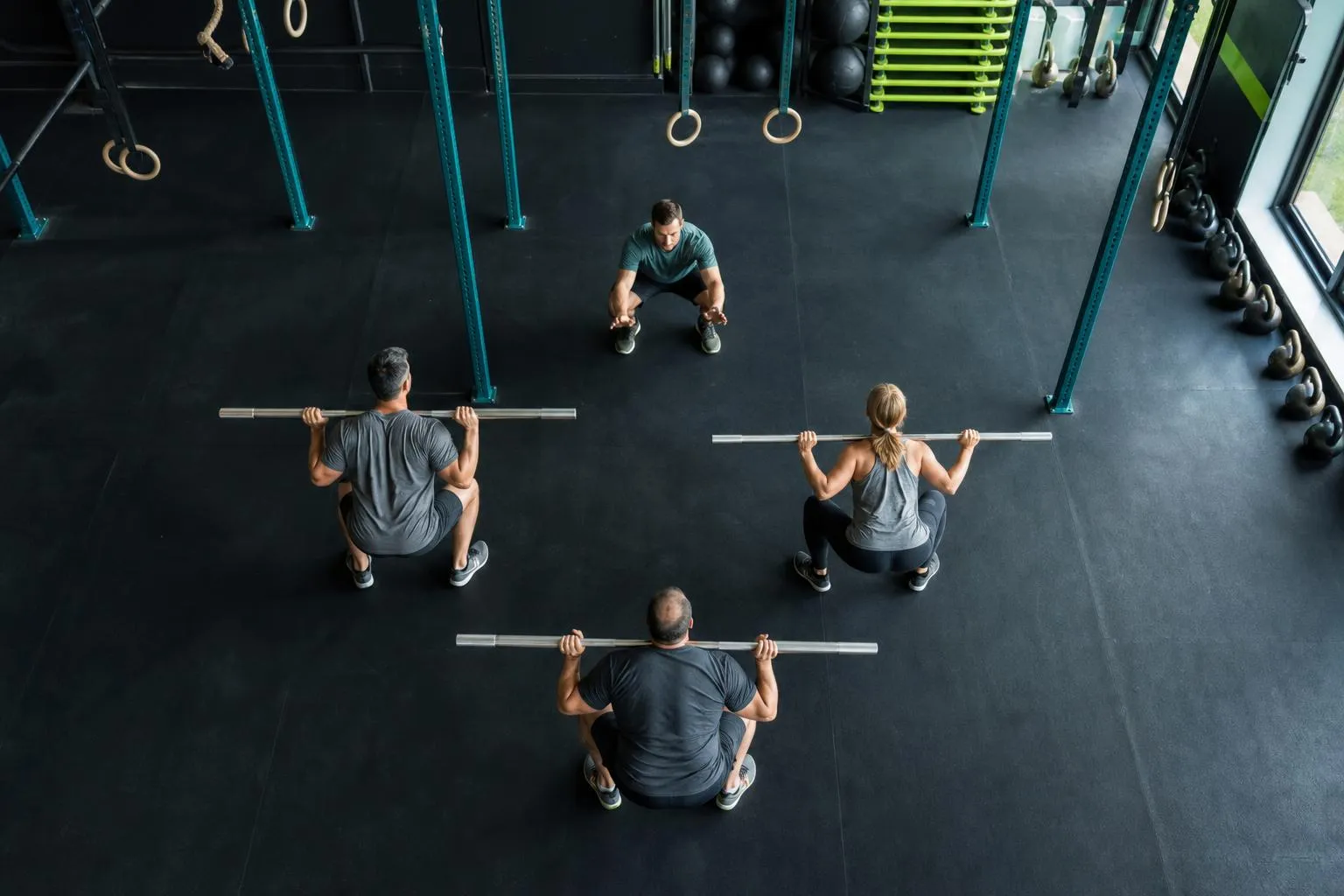 Groupe en squat avec barres dans une salle de sport