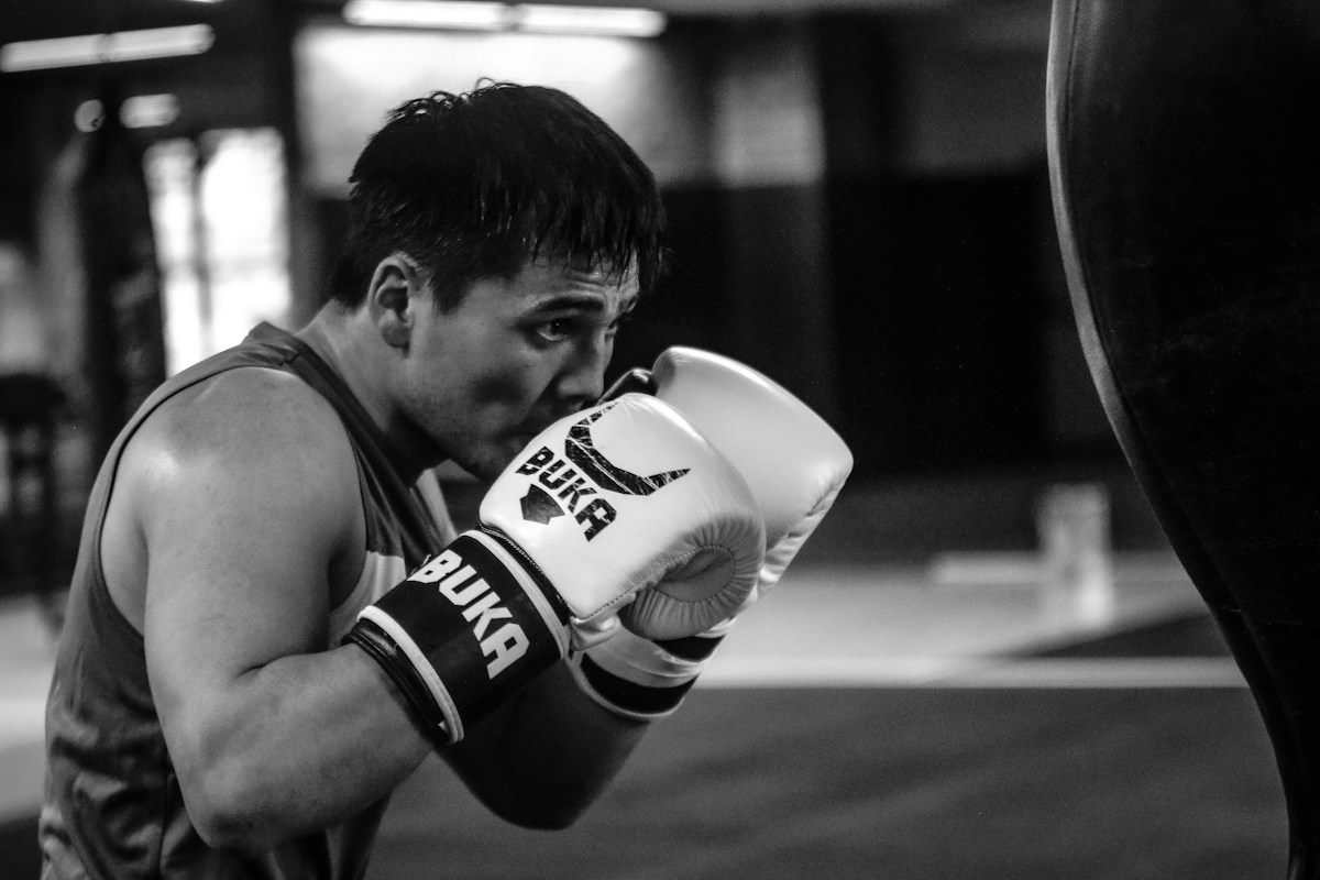 Boxeur en salle d’entraînement frappant un sac de boxe.