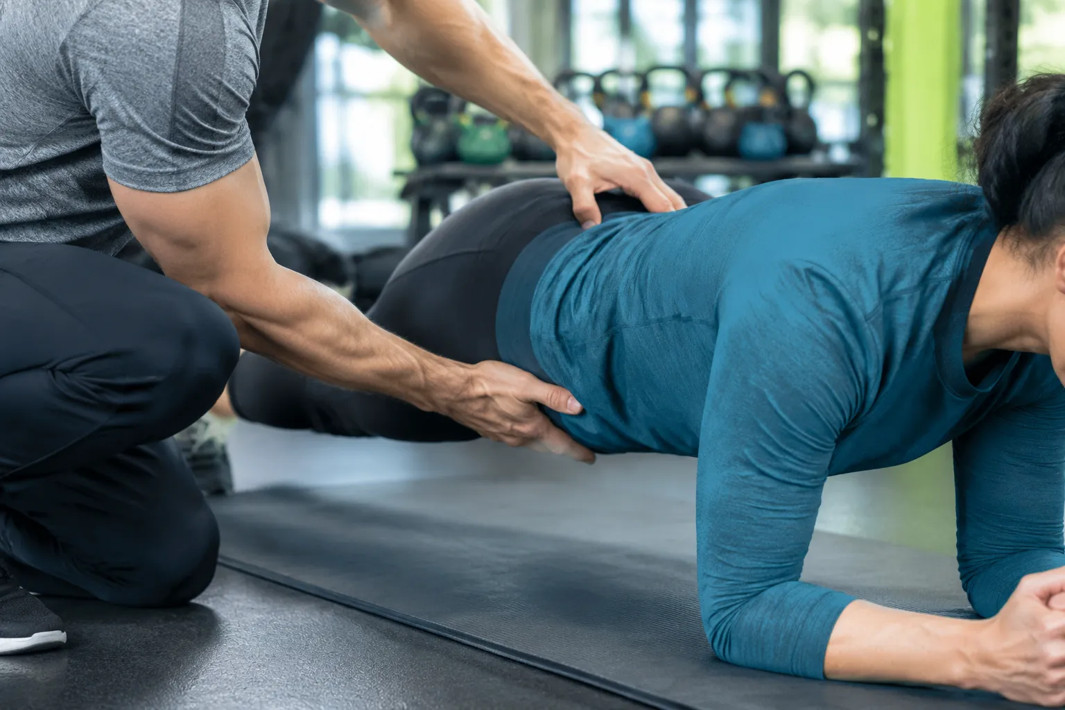 Kinésithérapeute corrigeant la posture d’une femme sur tapis de sport